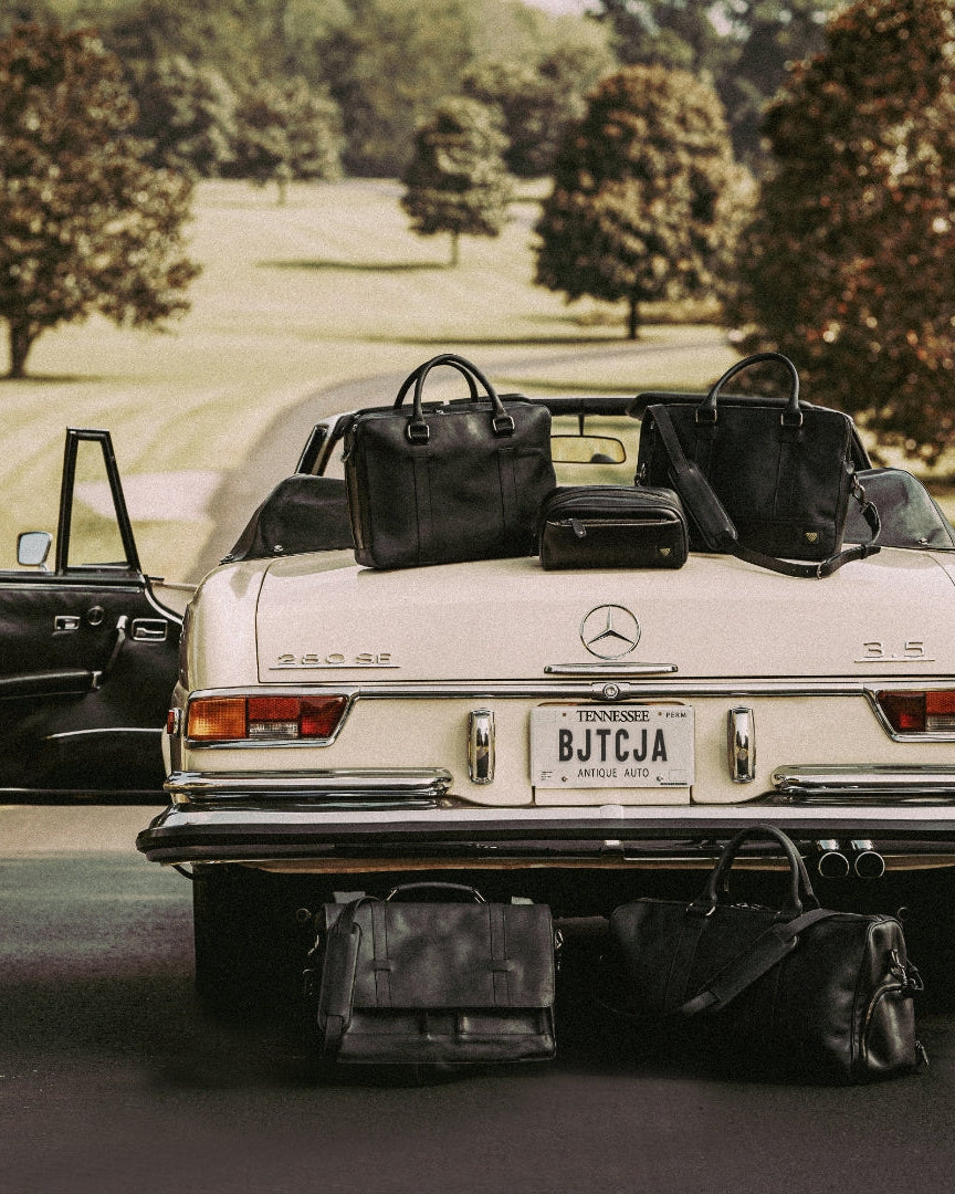 Luxurious black leather bags displayed with a vintage car, highlighting both style and elegance.