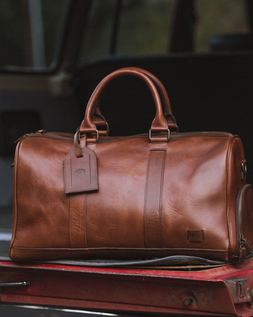 High-quality leather duffle with robust carry handles, adjustable shoulder strap, and large zippered opening.