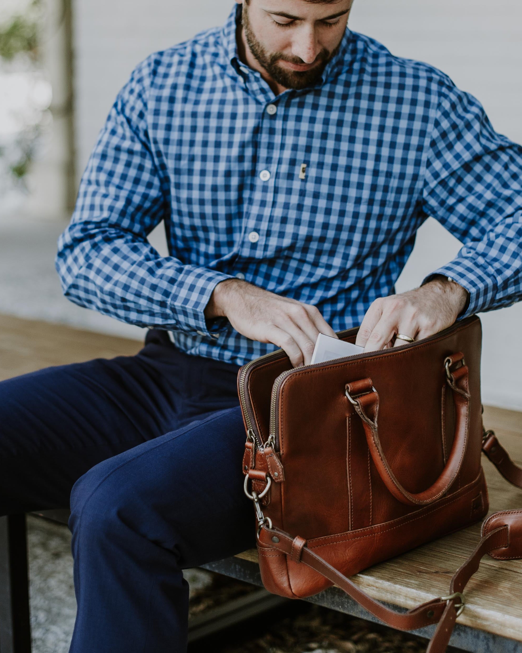 Stylish man accessing contents of a sophisticated leather attache bag. Men's Best Leather Attache | Elderwood hover