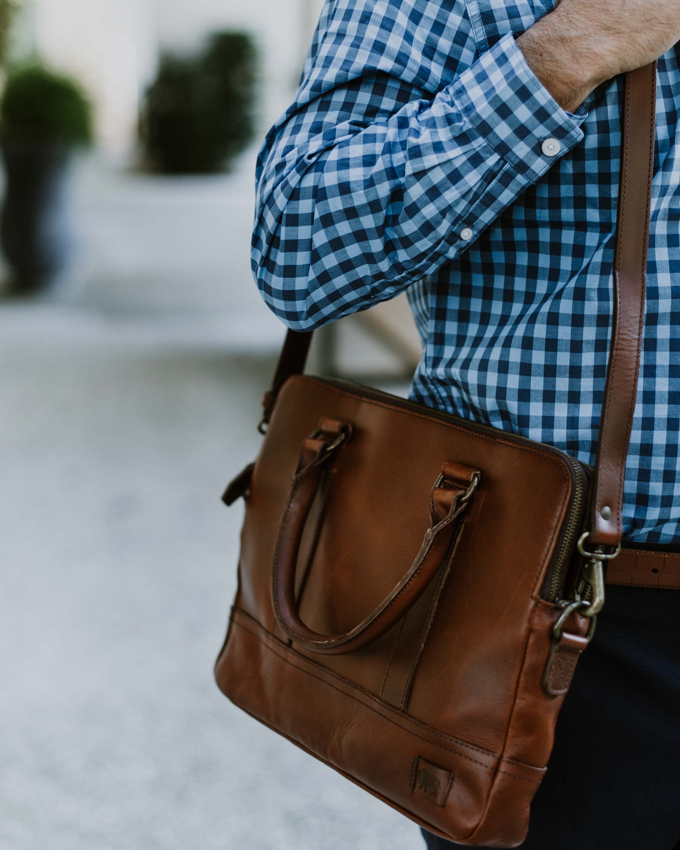 Man in blue checked shirt using a refined leather briefcase.