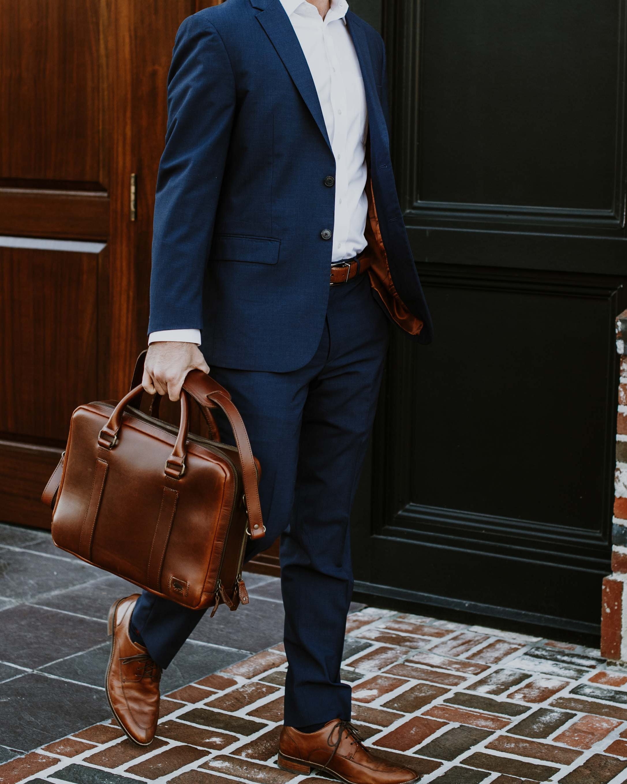 Stylish tan leather briefcase, seamlessly matching business attire, with elegant lines and polished hardware for a sophisticated look.