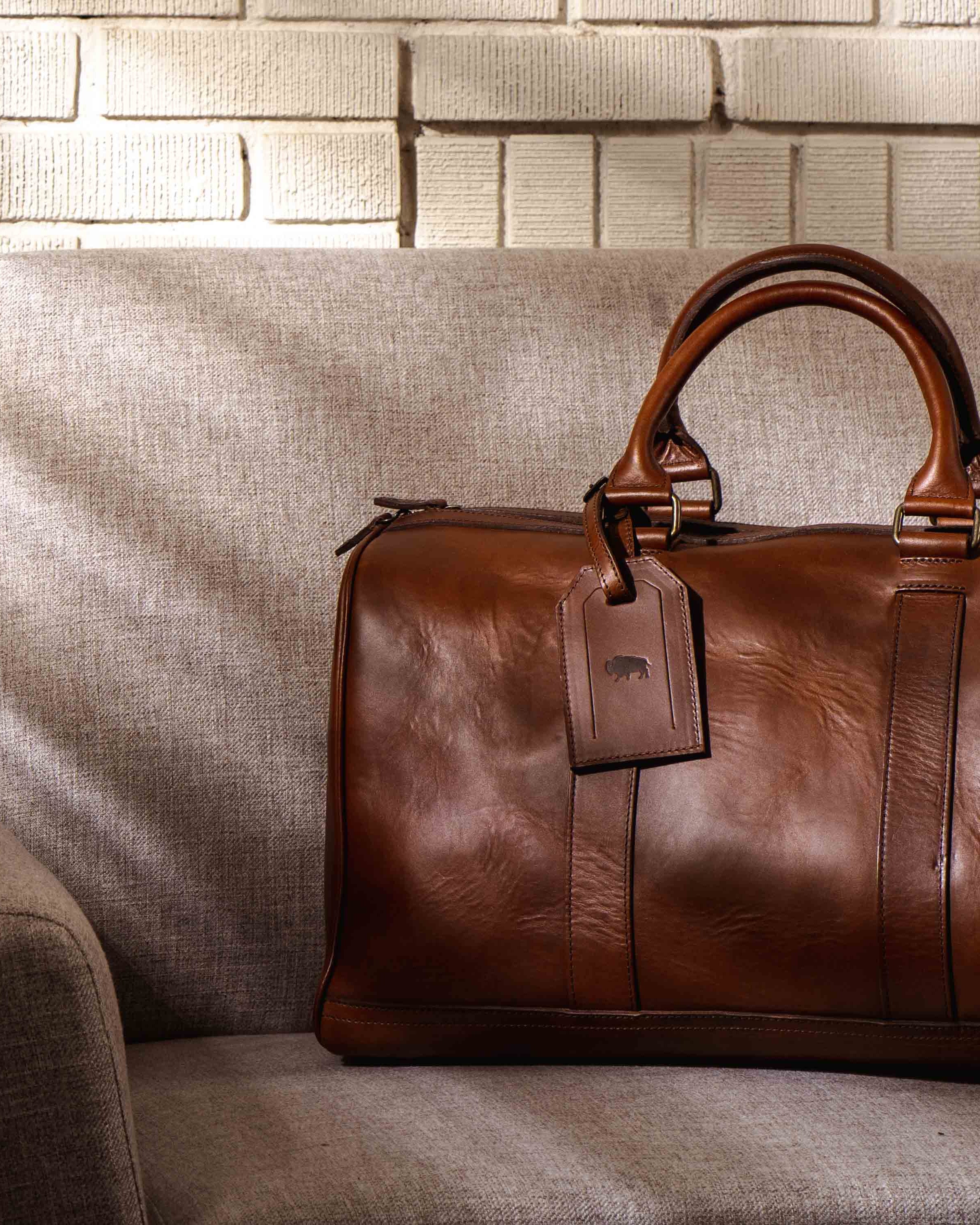 Chic tan leather duffle, perfect for jet-setters, with a minimalist design and functional elegance.