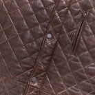 Brown leather vest with a quilted pattern, featuring snap buttons and a sleek silhouette.